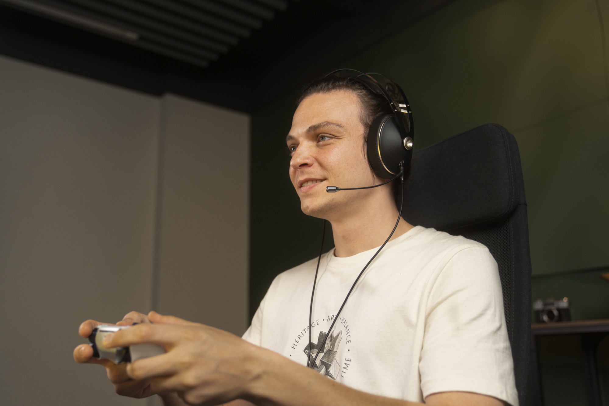 Photo of man wearing Meze headphones with boom mic playing a video game