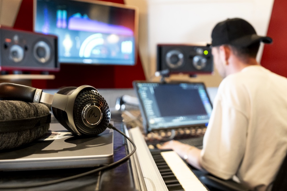 Image of Focal Lensys on music equipment in a studio room, with a music producer in the background