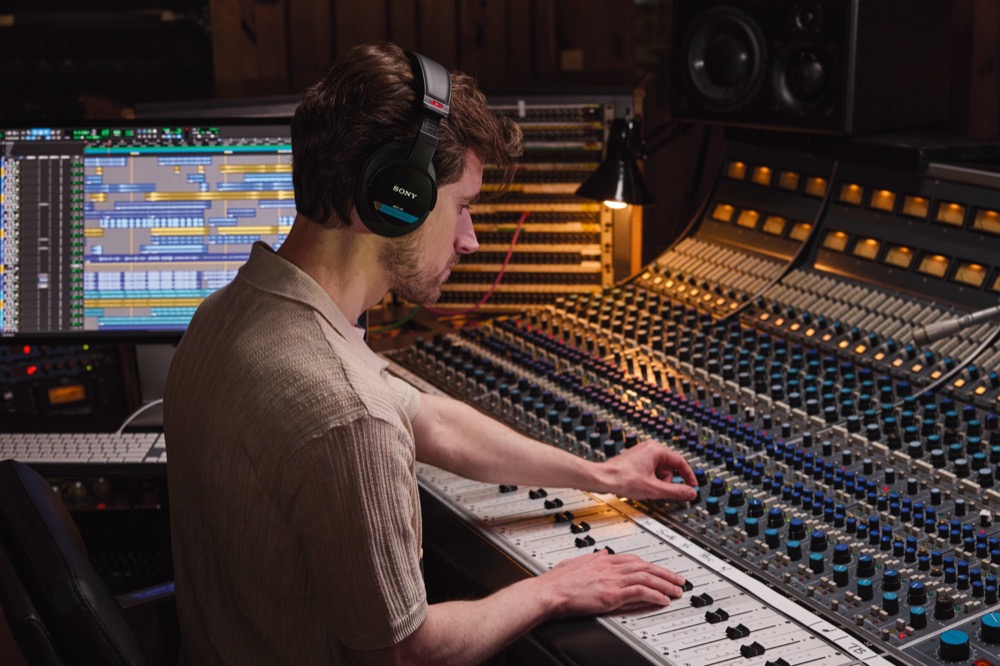 Photo of studio engineer using Sony MDR-M1 while using mixing console