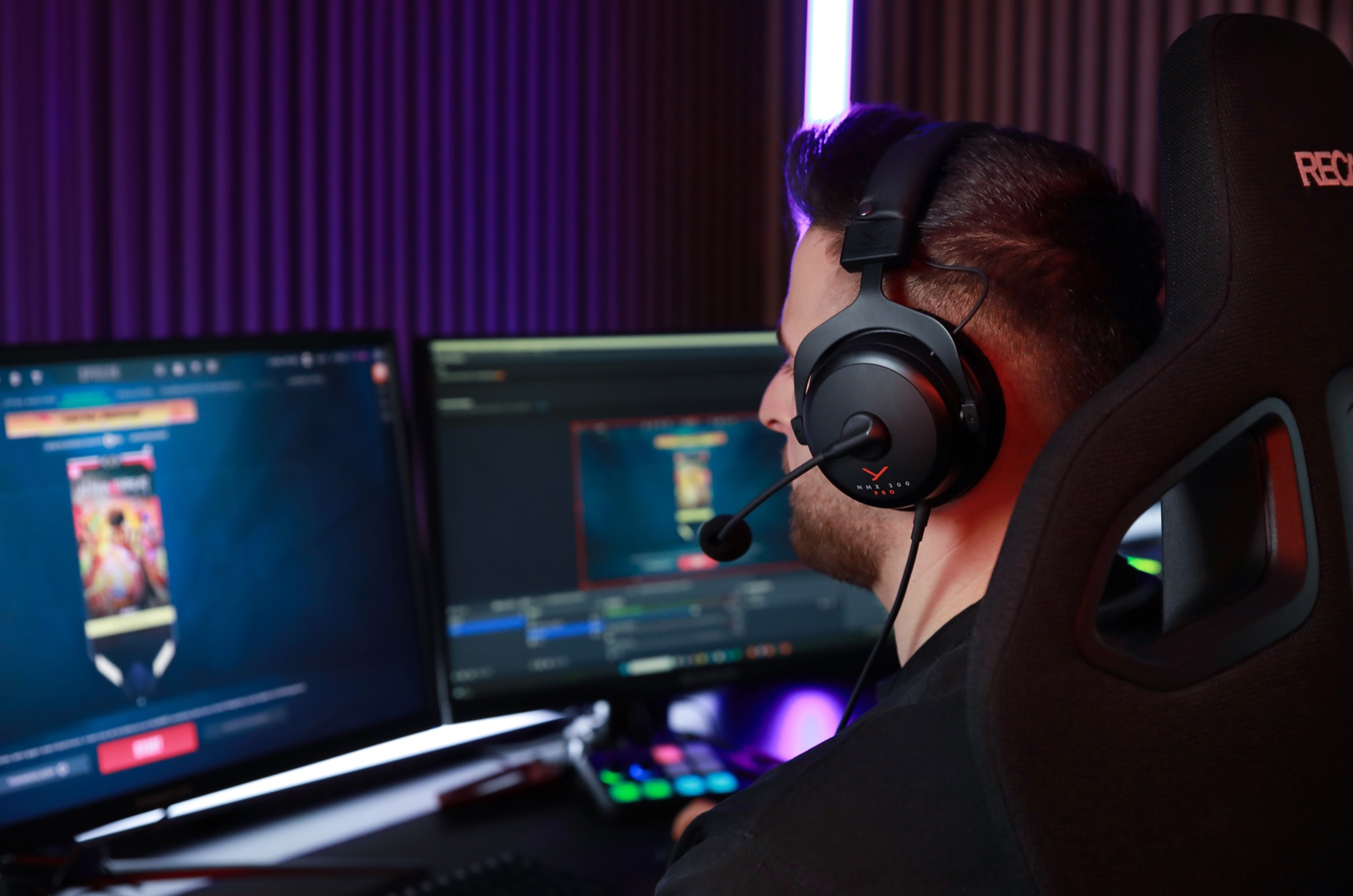 A man sits at a desk staring at a computer monitor, playing a game while wearing the Beyerdynamic MMX 300 headset